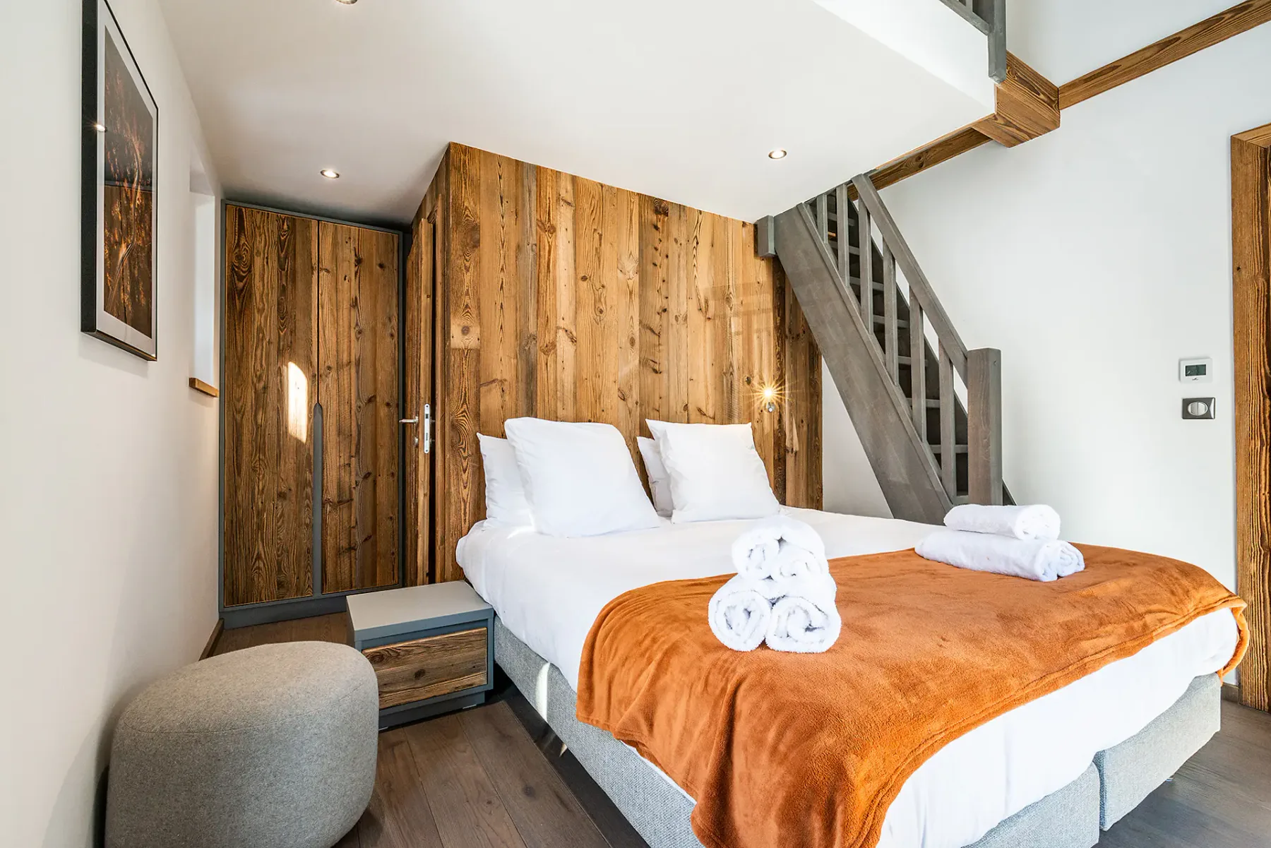 Un dormitorio con una cama doble, una manta naranja y paneles de madera.