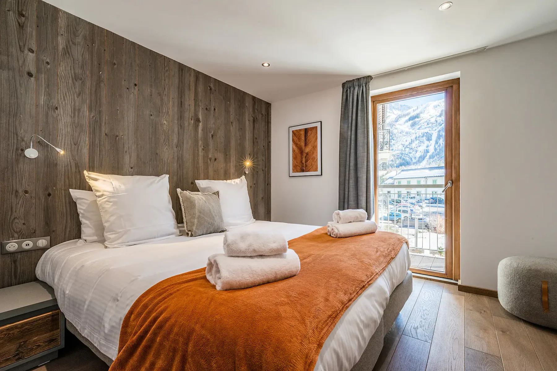 Un dormitorio con cama doble, toallas dobladas y una ventana con vistas a la montaña.