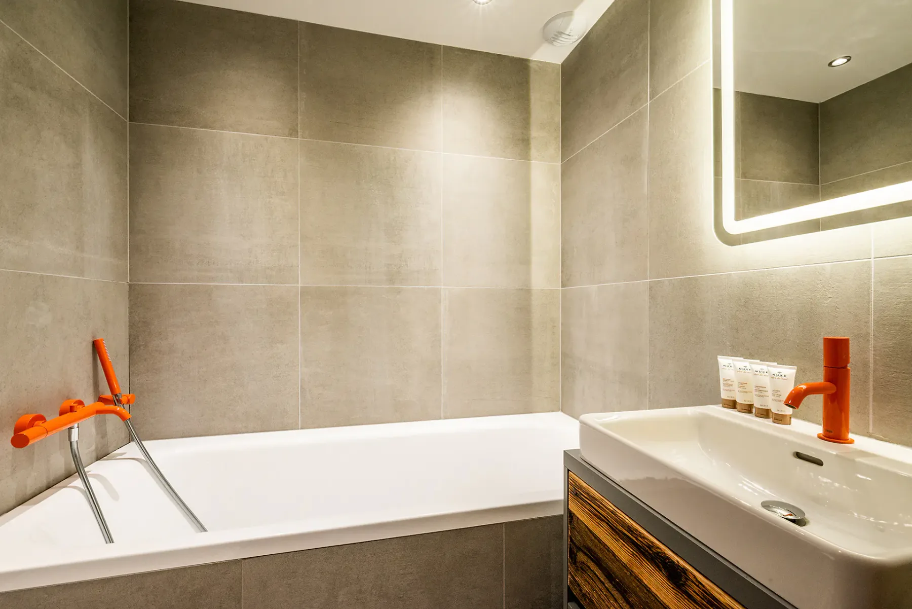 Un baño revestido de azulejos, con bañera y lavabo bajo un espejo.