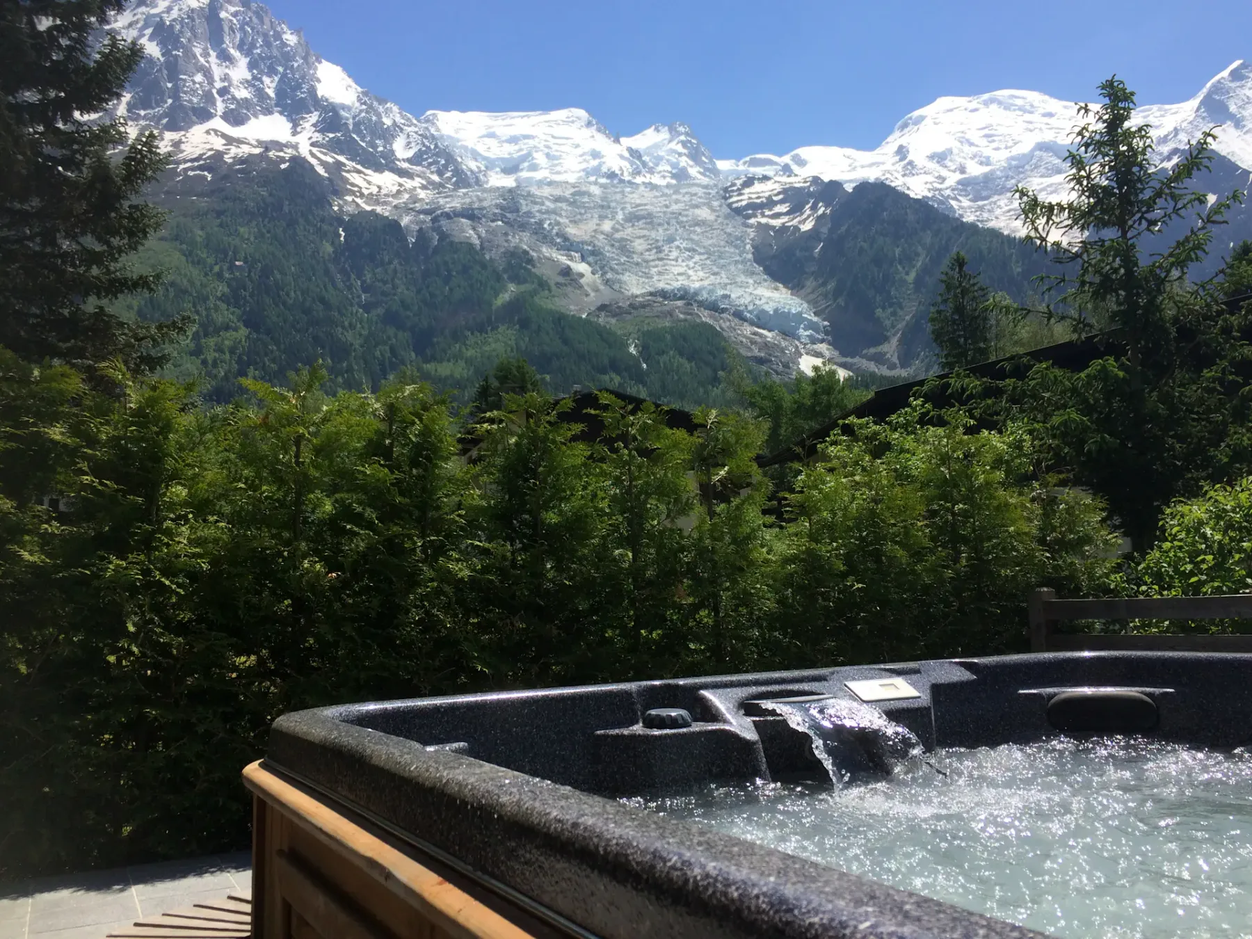 Una bañera de hidromasaje al aire libre mira hacia laderas boscosas y montañas nevadas.