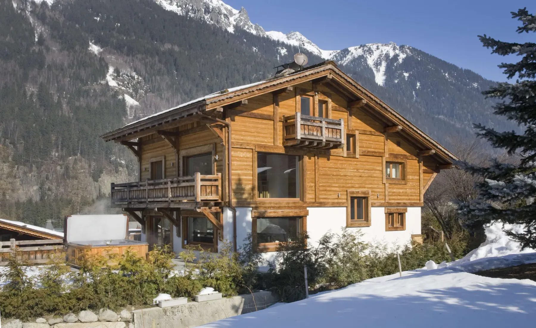 Un chalet de madera se encuentra entre montañas nevadas.