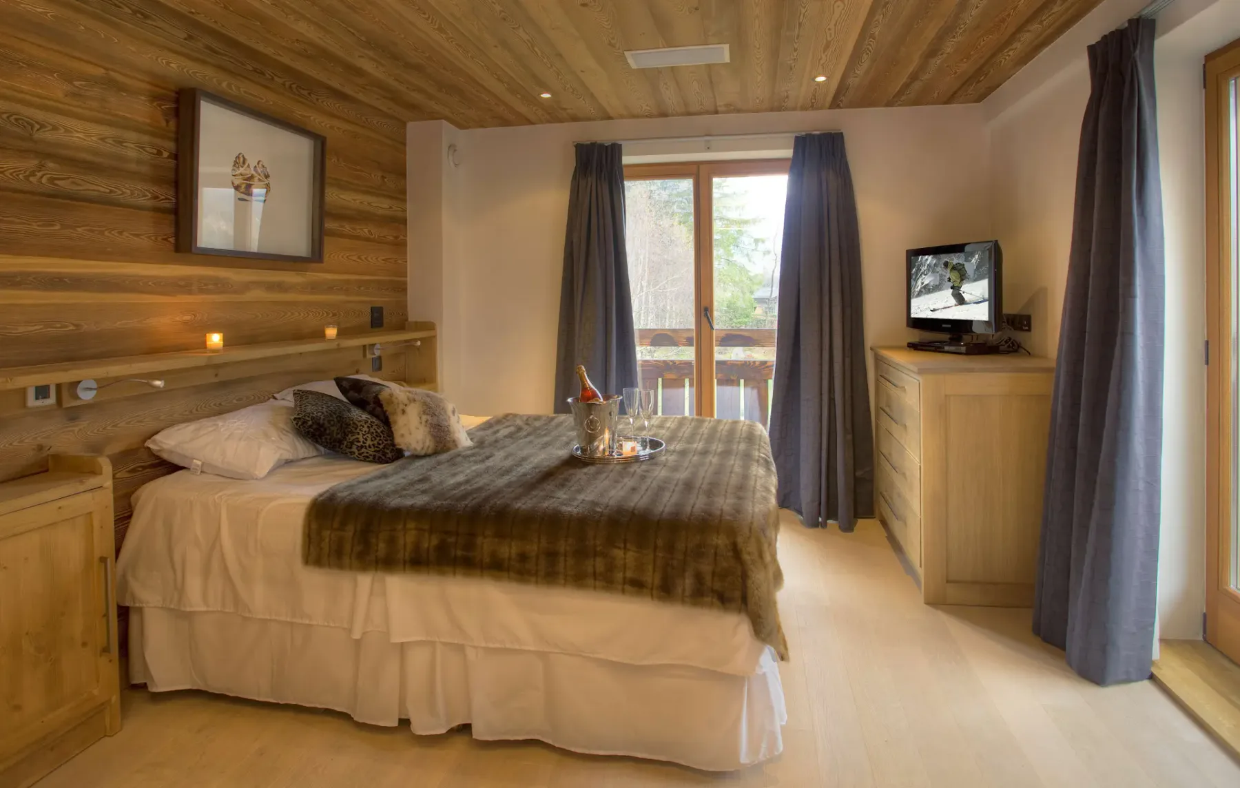 Un dormitorio con una cama doble, muebles de madera y puertas de vidrio que dan a un balcón.