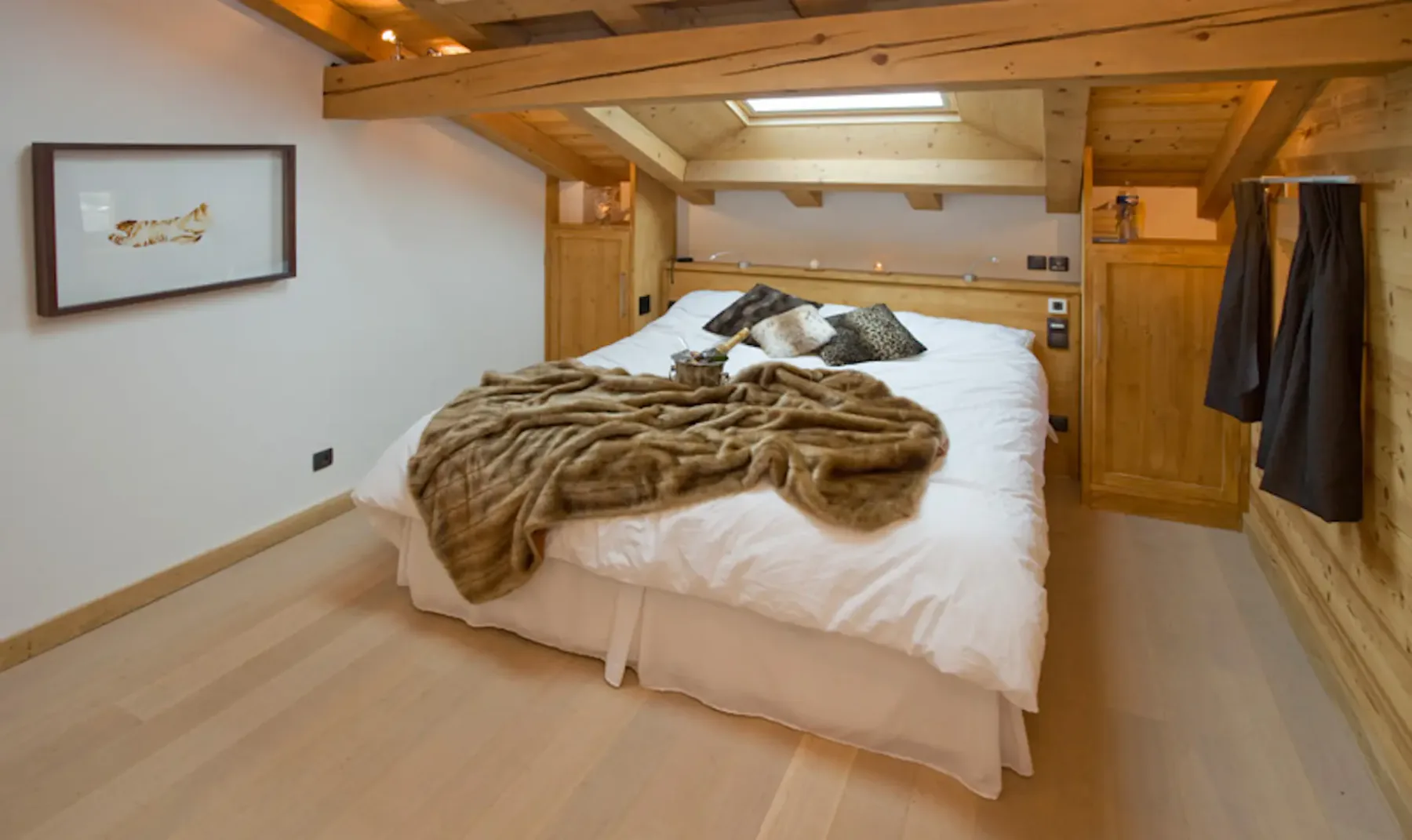 Dormitorio con una cama grande bajo vigas de madera a la vista.