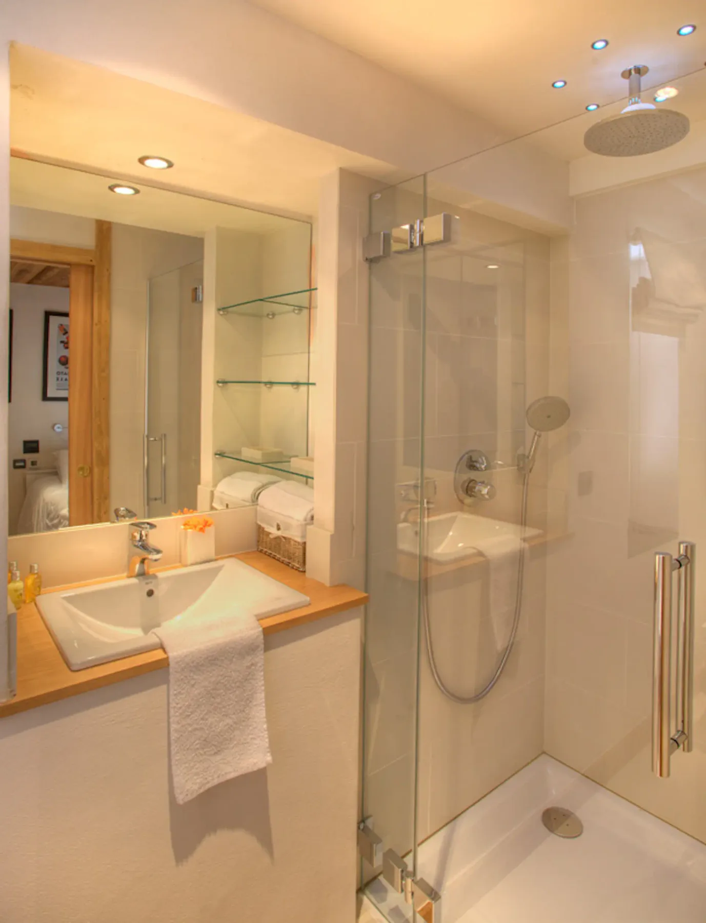 Un baño con lavabo, espejo y ducha con mampara de vidrio.