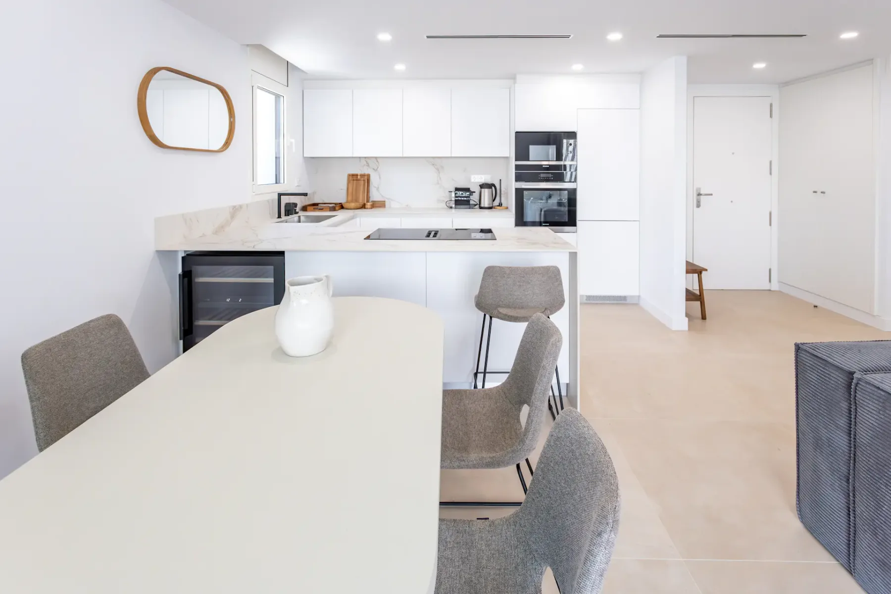A bright kitchen and dining area with white cabinetry and a long dining table.