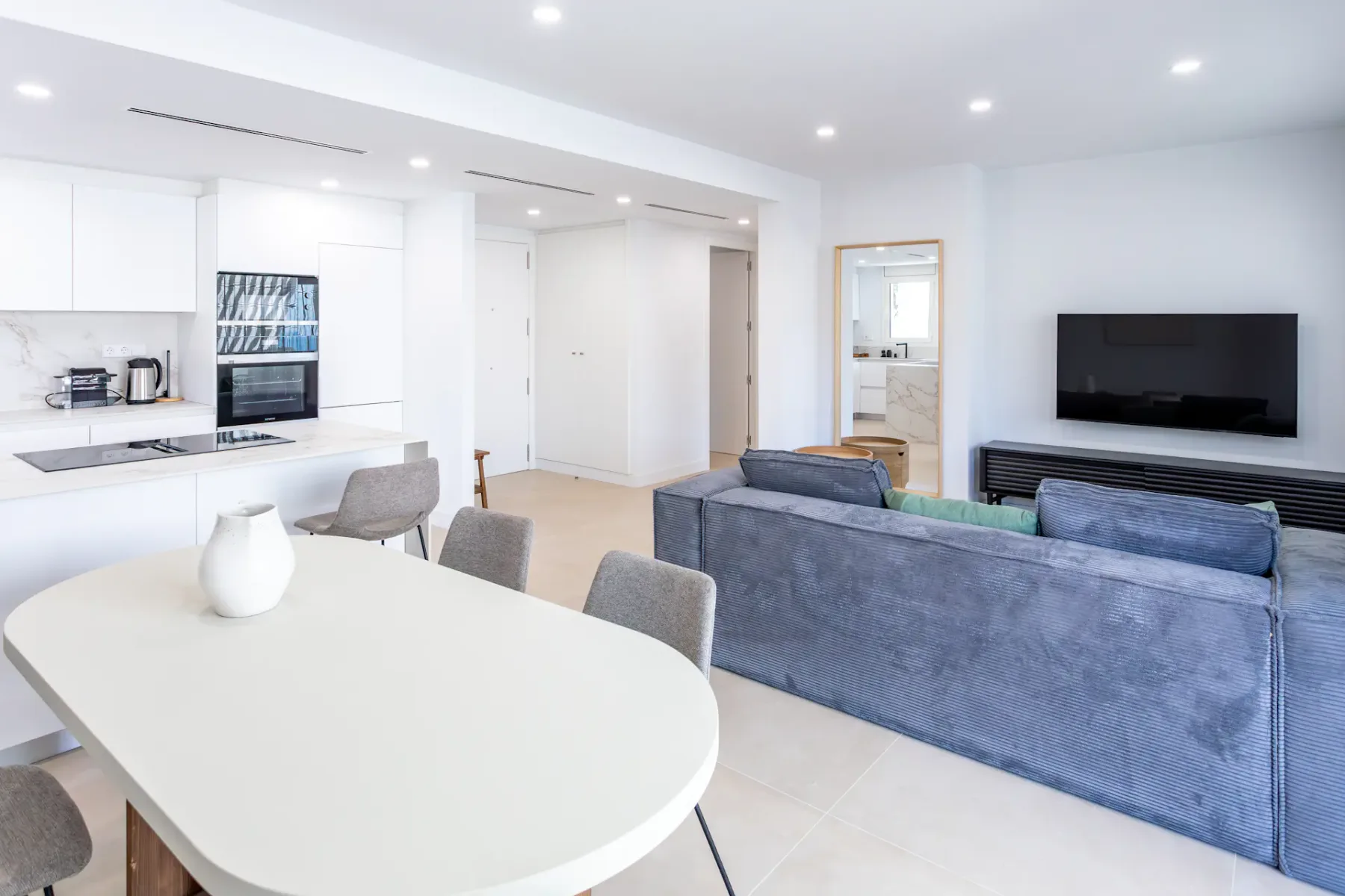 A bright open-plan living and dining area with a kitchen and television.
