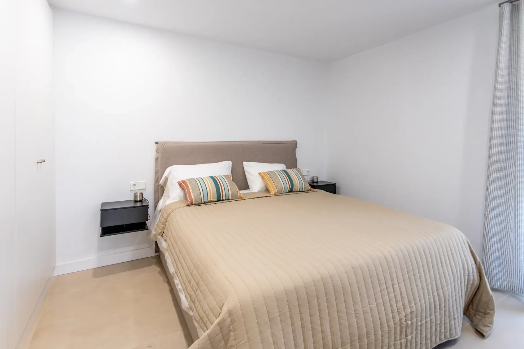 A bedroom with a neatly made bed and striped accent pillows.