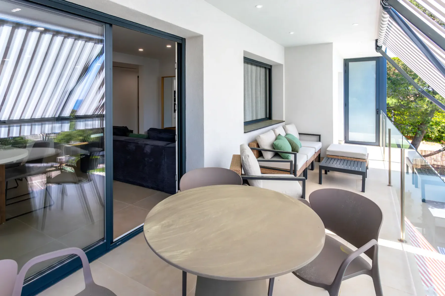 A bright balcony seating area with a round table and cushioned bench.