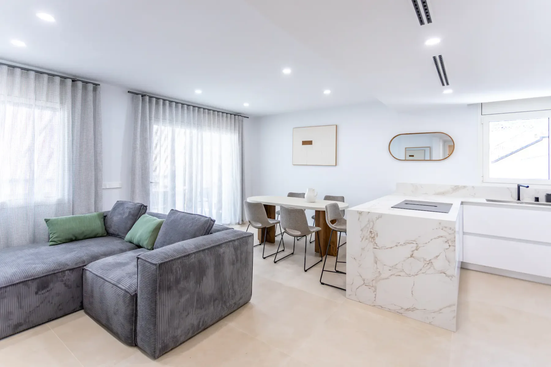 A bright open-plan living area with seating, a dining table, and a kitchen island.