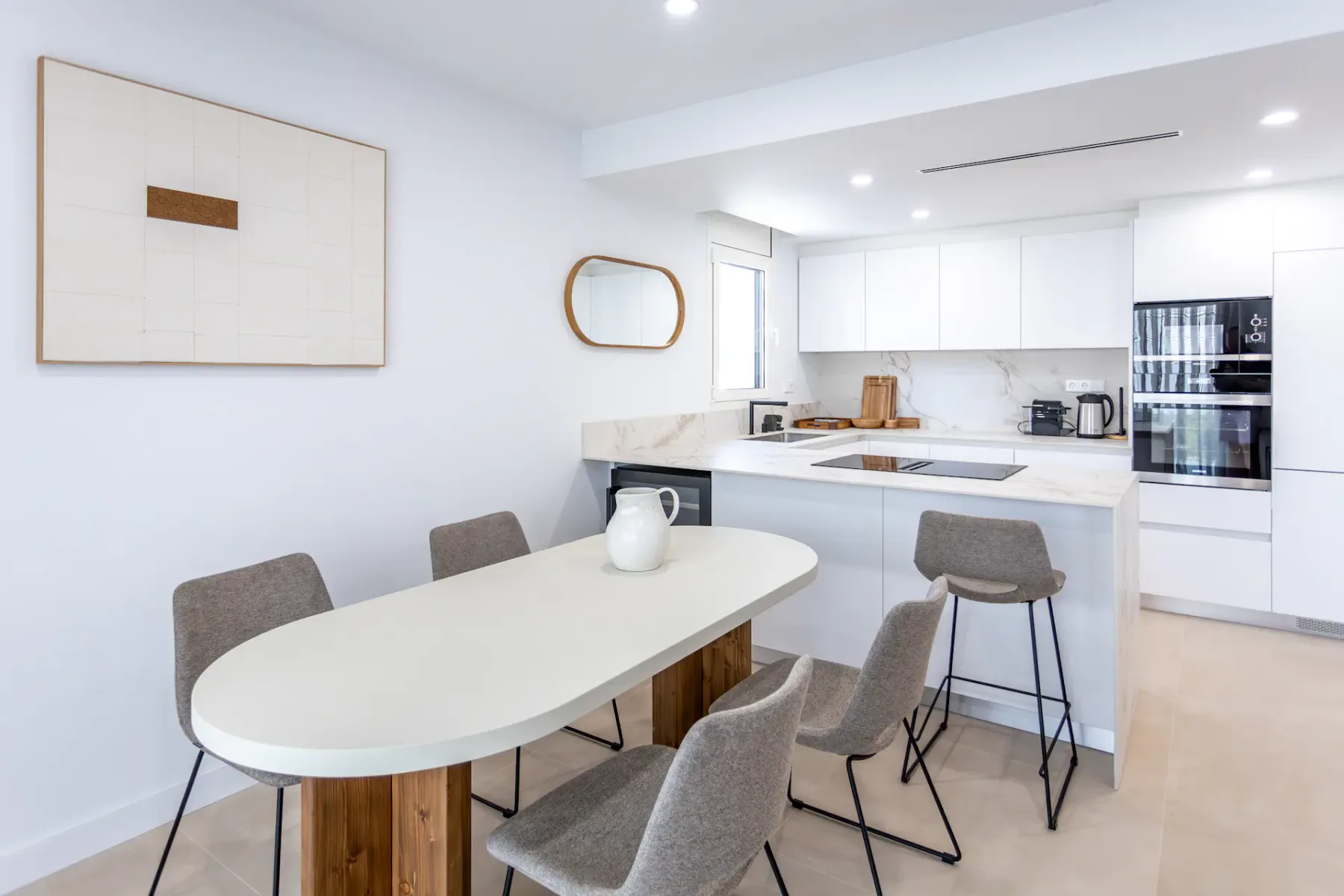 A bright kitchen and dining area with a white table and gray seating.