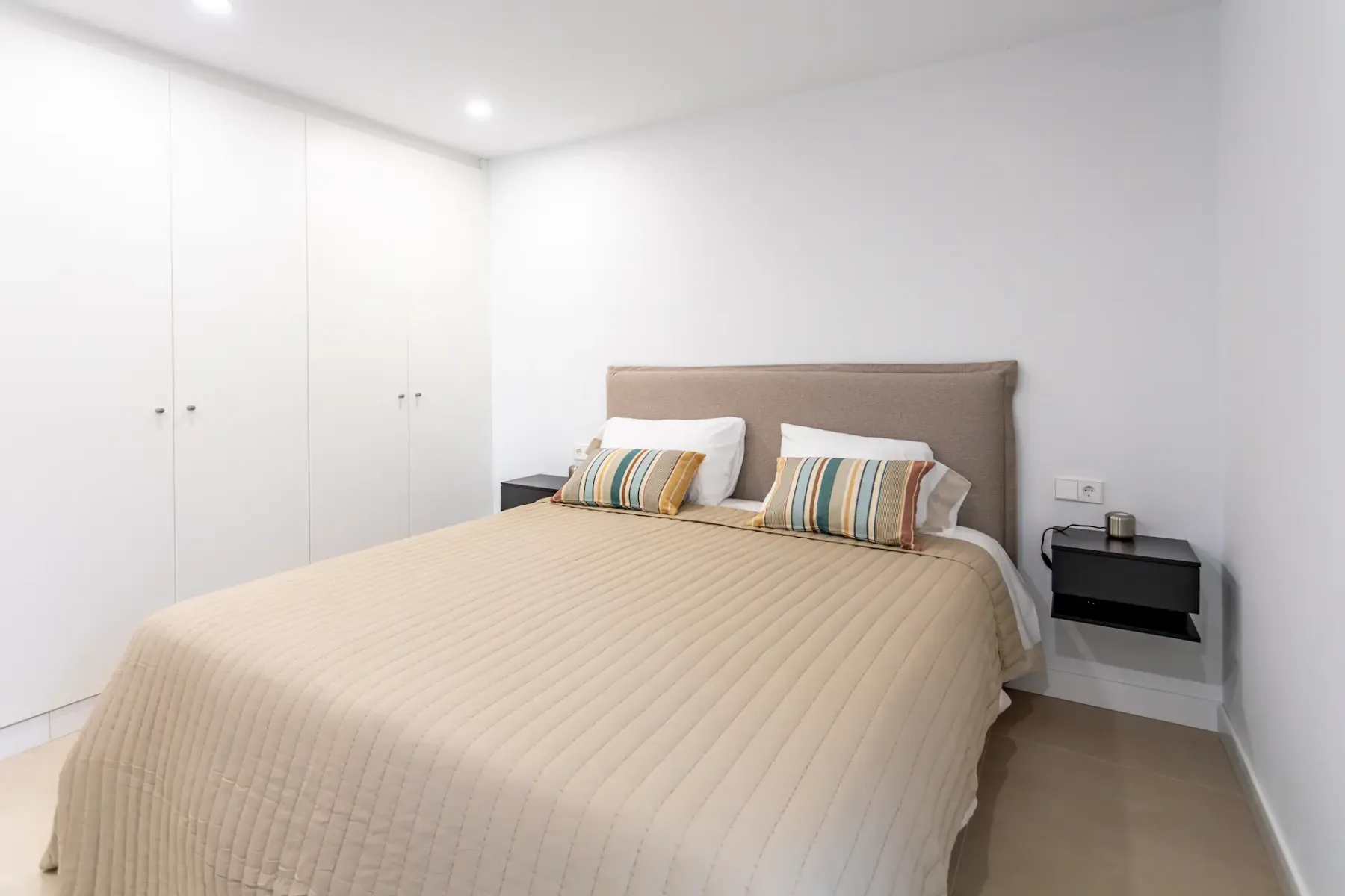 A bedroom with a neatly made bed and built-in wardrobes.
