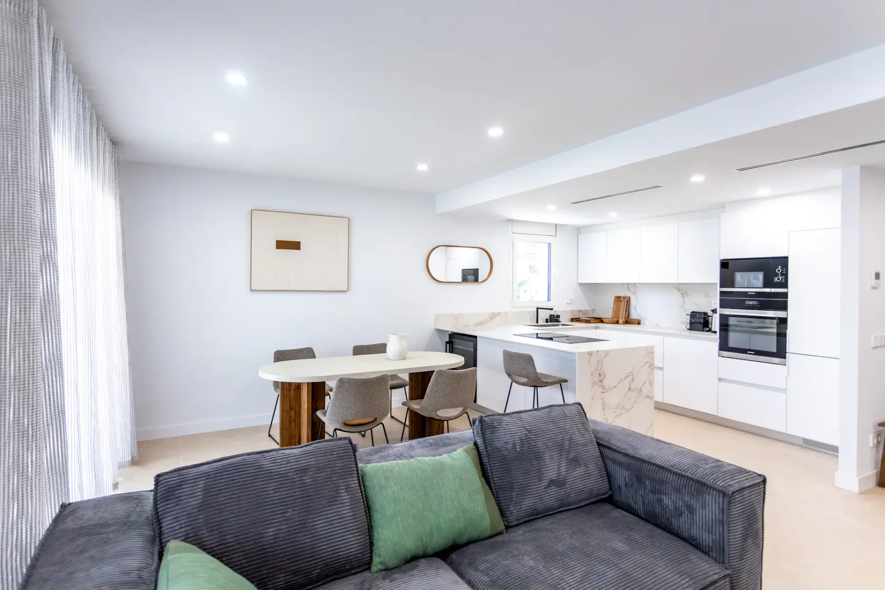 A bright open-plan living and kitchen area with a dining table and seating.