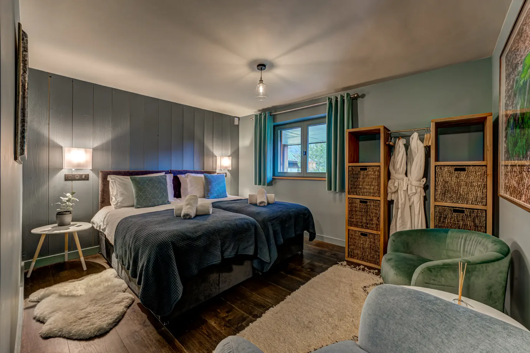 Bedroom with a dark upholstered bed, paneled headboard wall, curtained window, and open wardrobe.