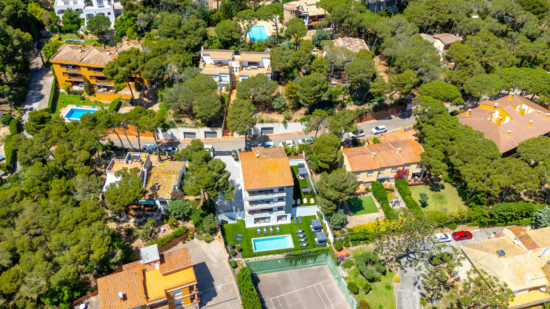 Shared amenity: An aerial view of buildings, trees, a swimming pool, and a sports court.