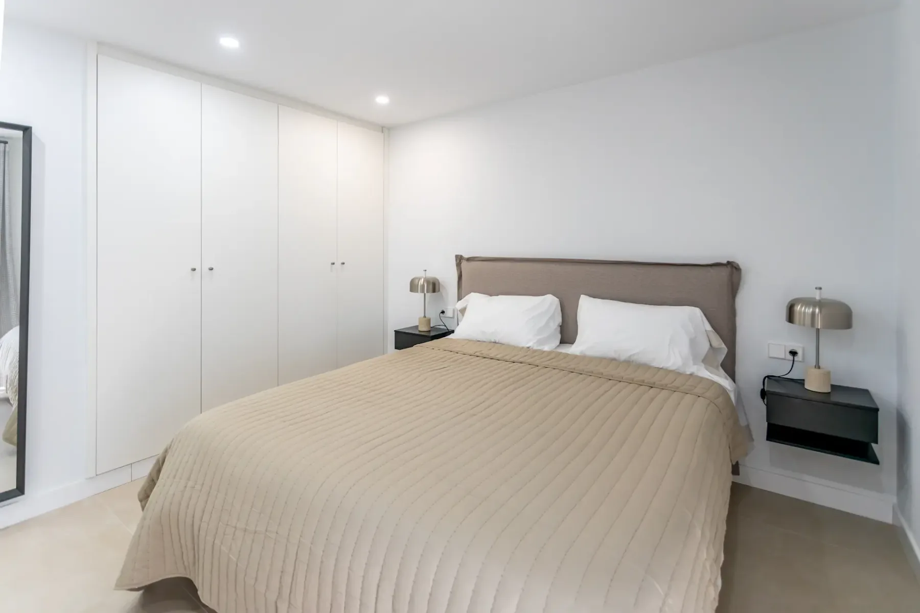 A bedroom with a double bed, bedside tables, and built-in wardrobes.