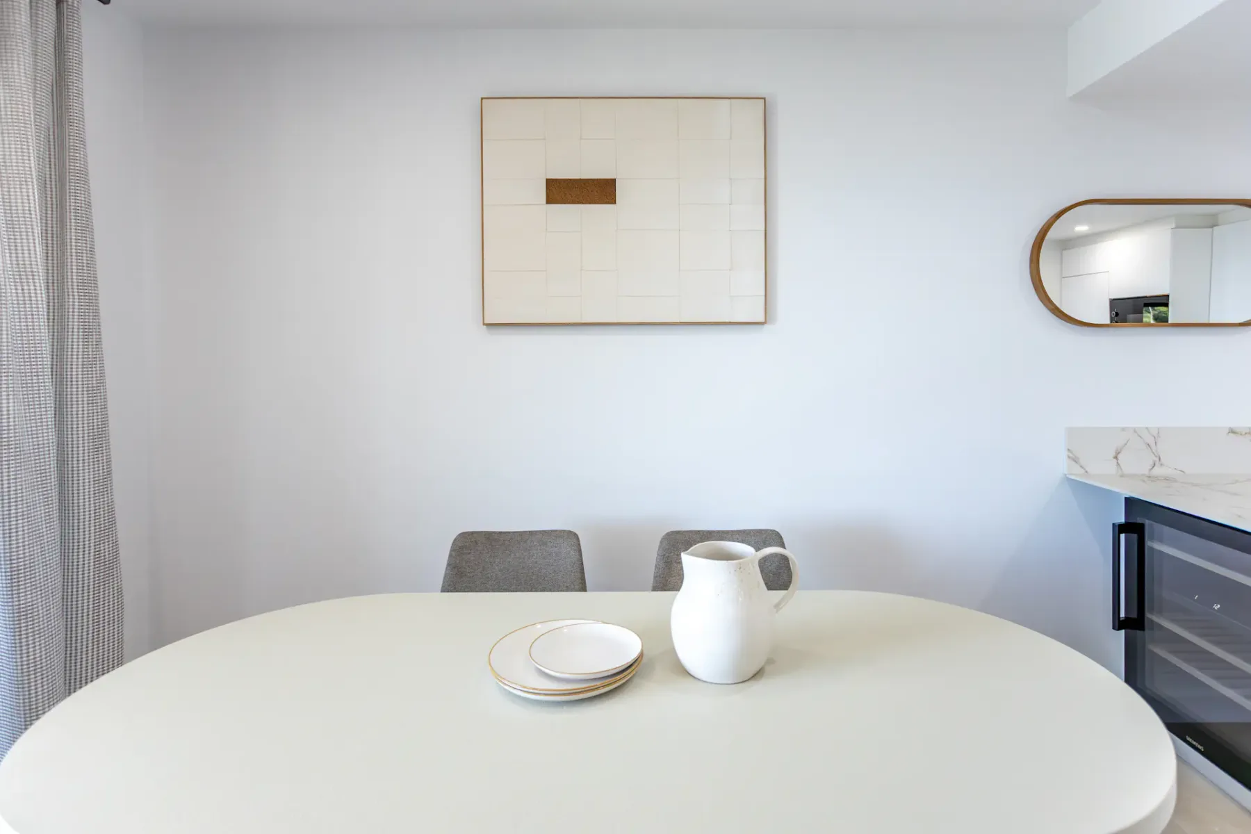 A dining area with a round table set with plates and a pitcher.