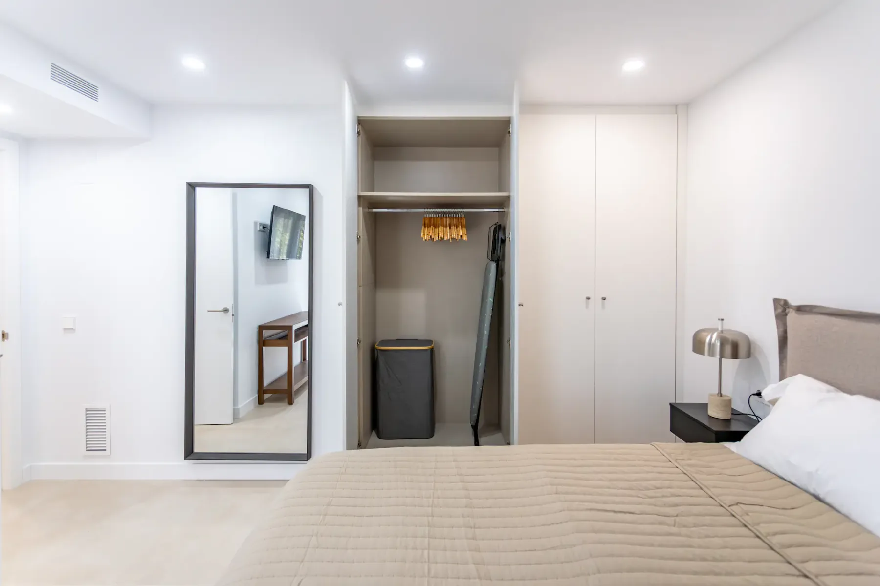 A bright bedroom with a neatly made bed and open closet.