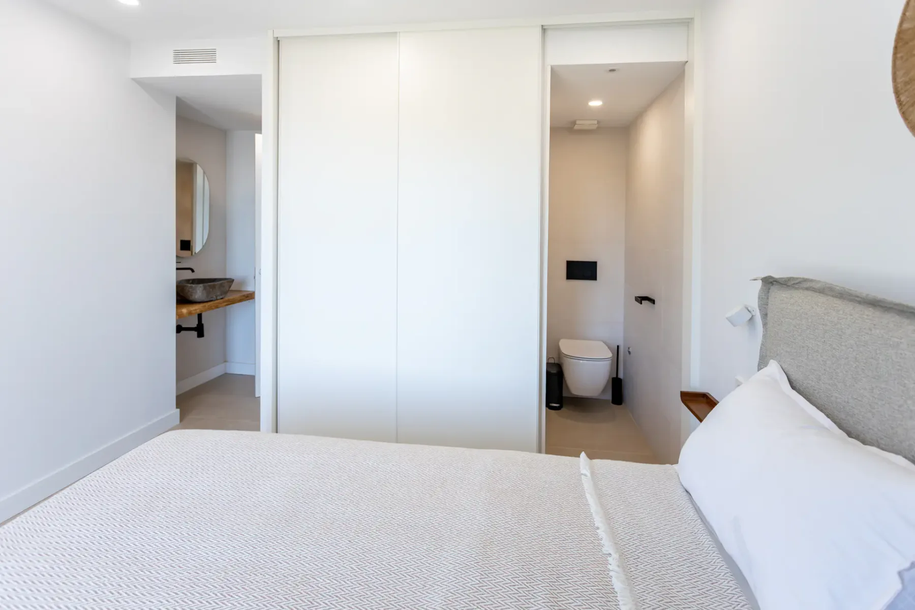 A bedroom with a bed facing sliding doors and an open bathroom doorway.