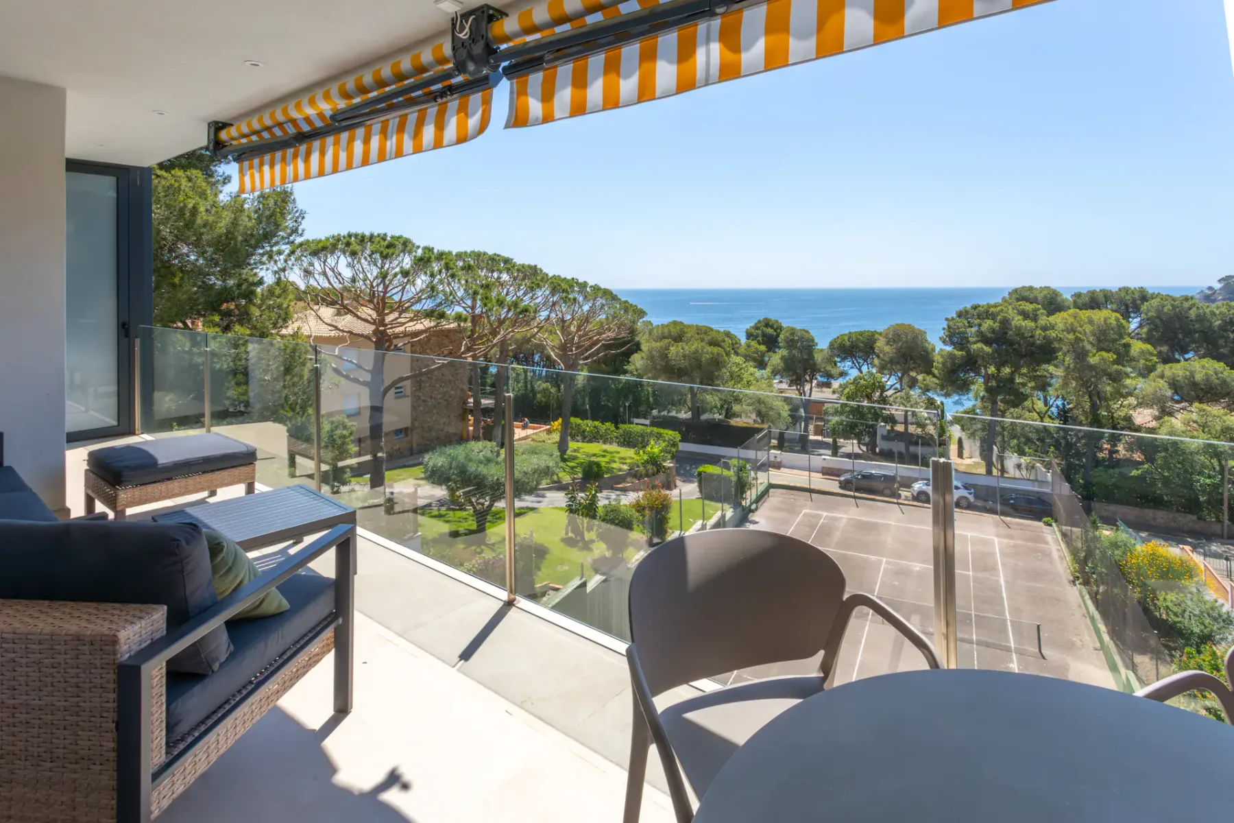 A balcony with seating overlooks landscaped grounds and the sea.