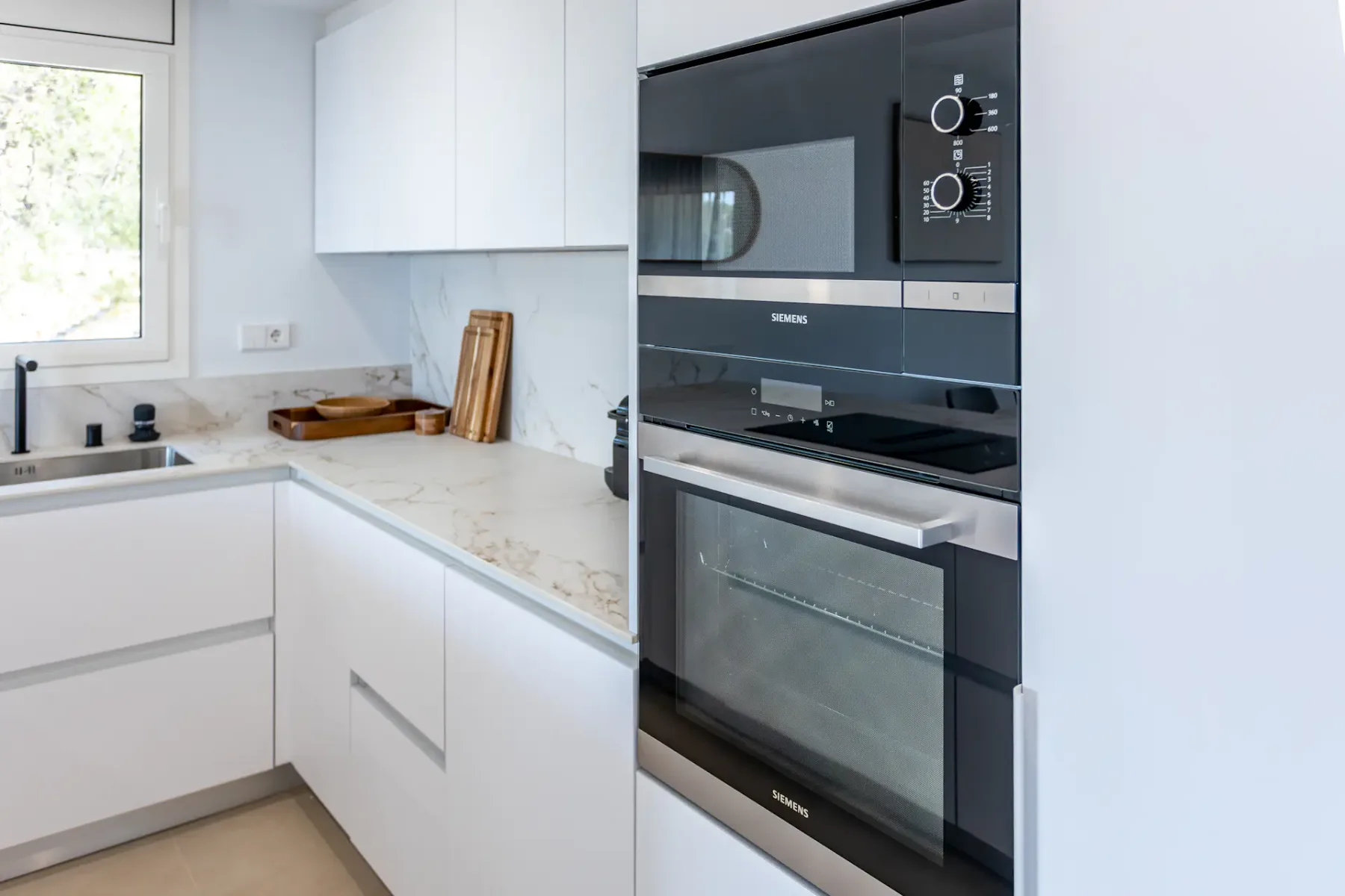 A bright modern kitchen with white cabinets and a built-in oven.
