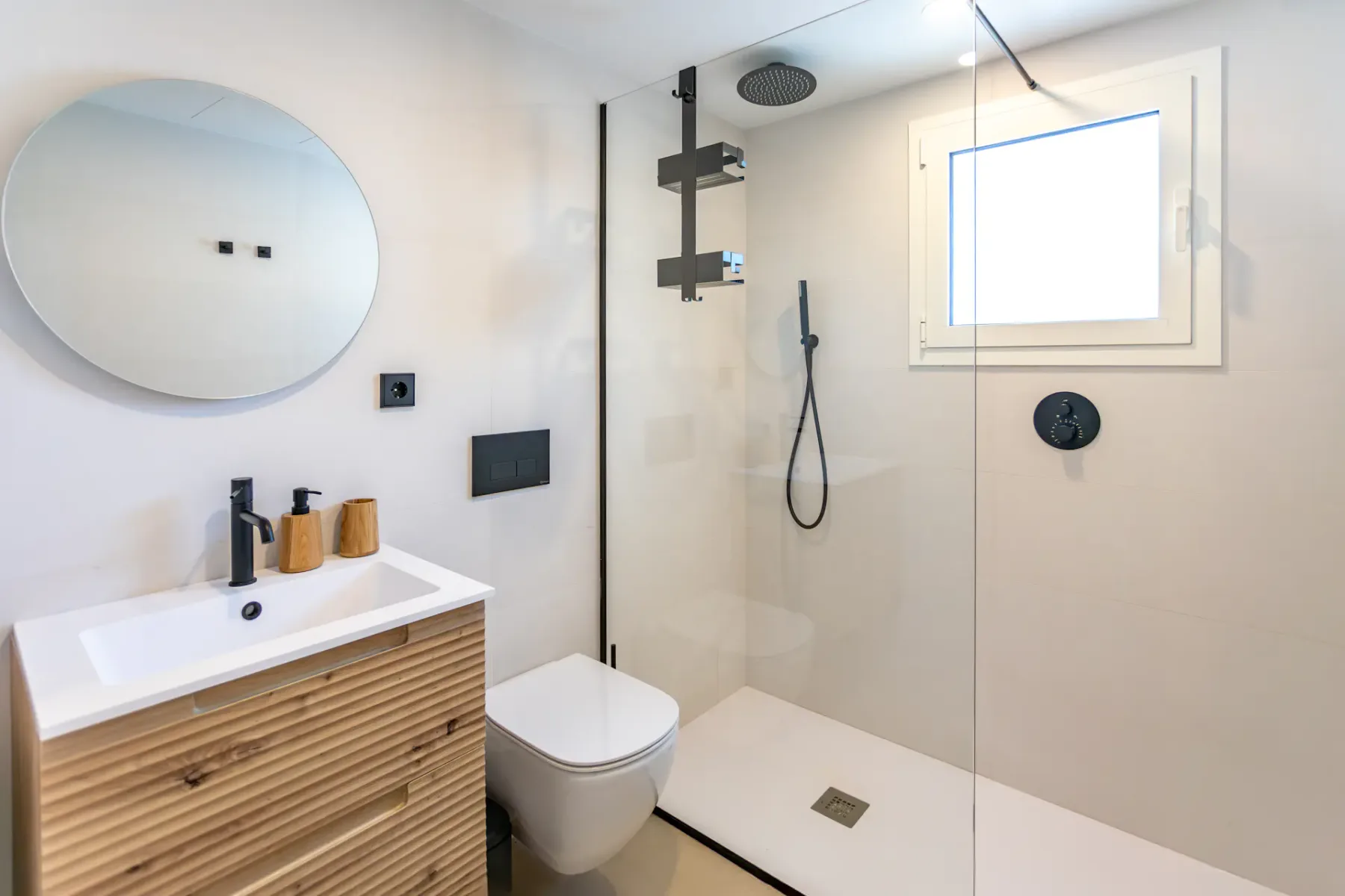 A modern bathroom with a vanity, toilet, and glass-enclosed shower.