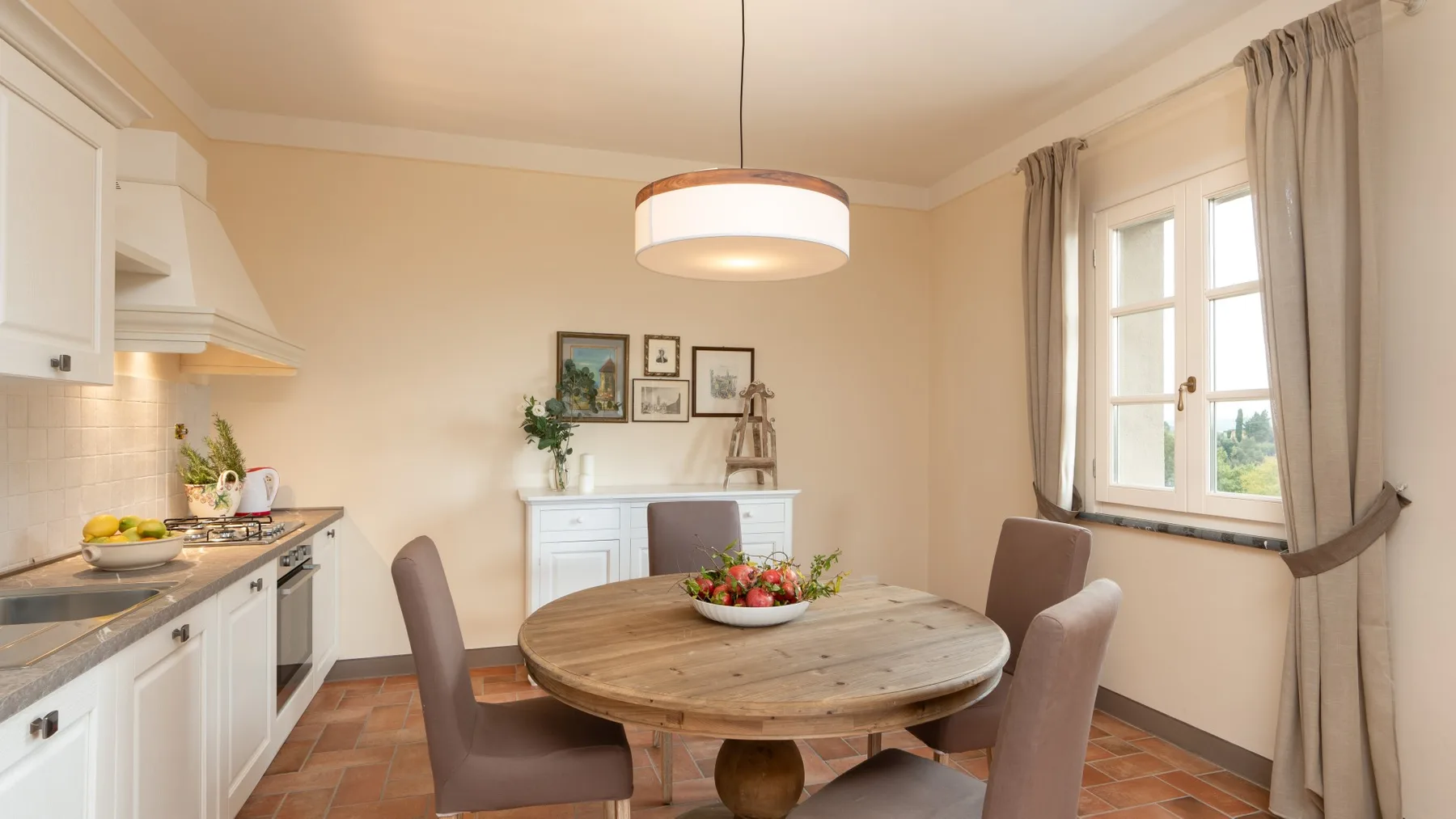 Un comedor luminoso con una mesa redonda de madera junto a ventanas con cortinas.