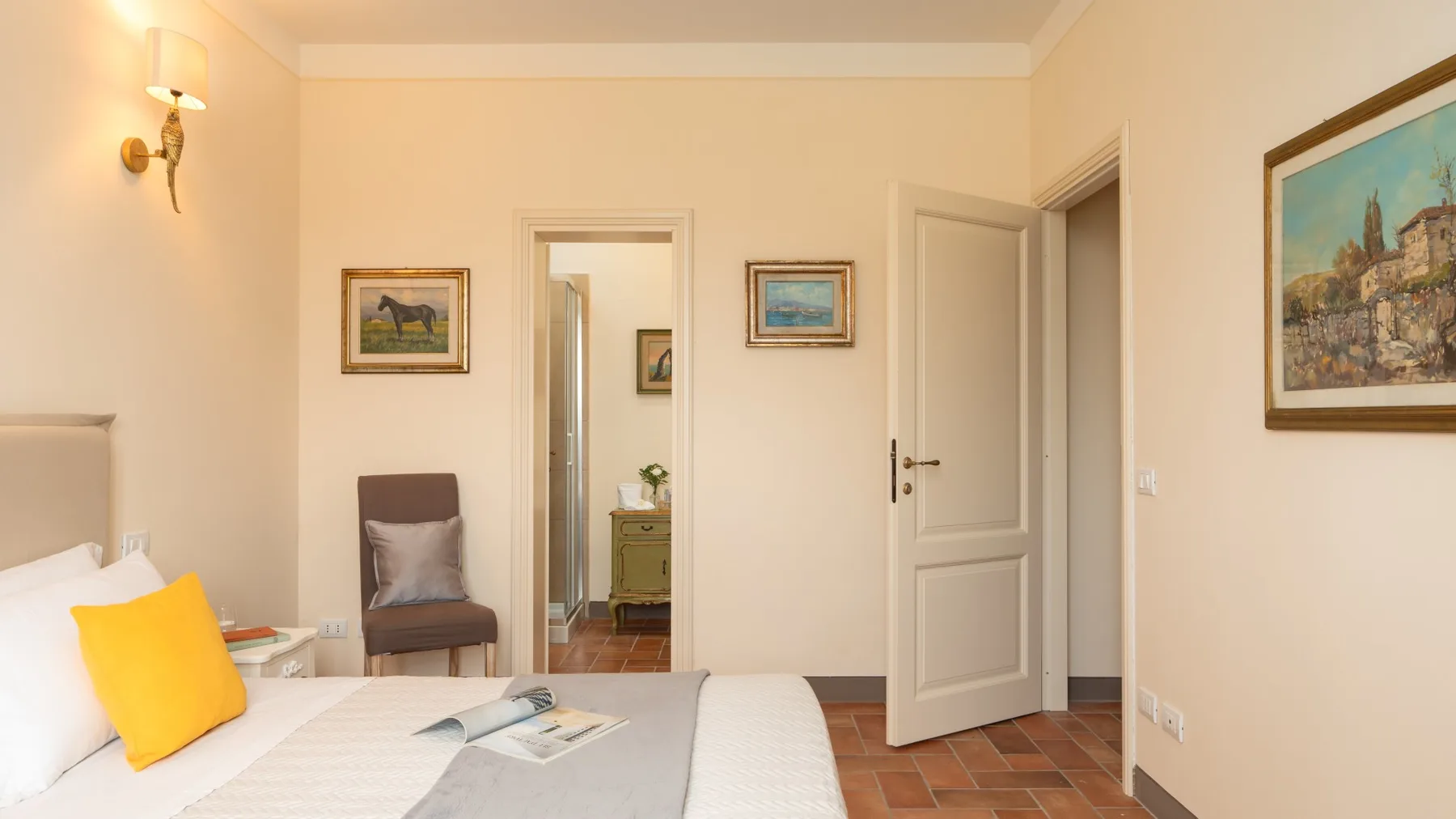 Un dormitorio con una cama, una mesita de noche y cuadros enmarcados.