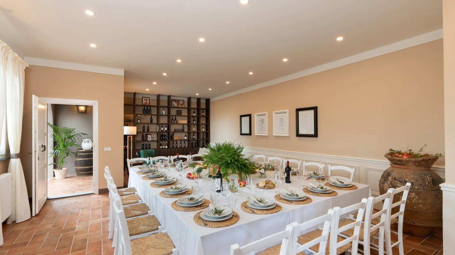 Un comedor con una mesa larga puesta para comer y una estantería junto a la pared del fondo.