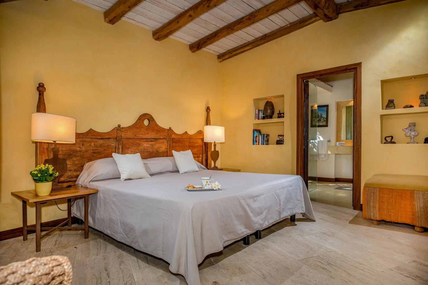 Un dormitorio con una cama grande, mesitas de noche y vigas expuestas en el techo.