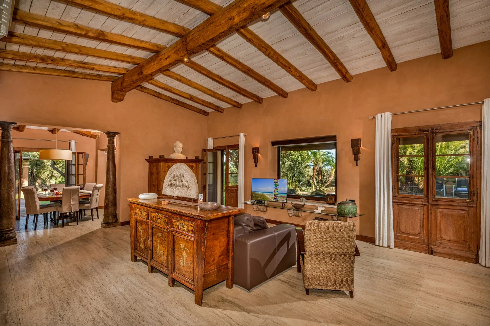 Una sala de estar con vigas de madera expuestas y asientos alrededor de un mueble central.