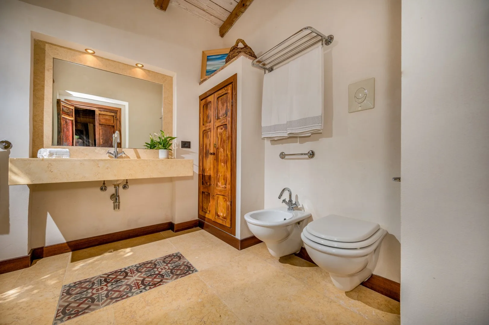 Un baño con lavabo, espejo, inodoro y toallero.