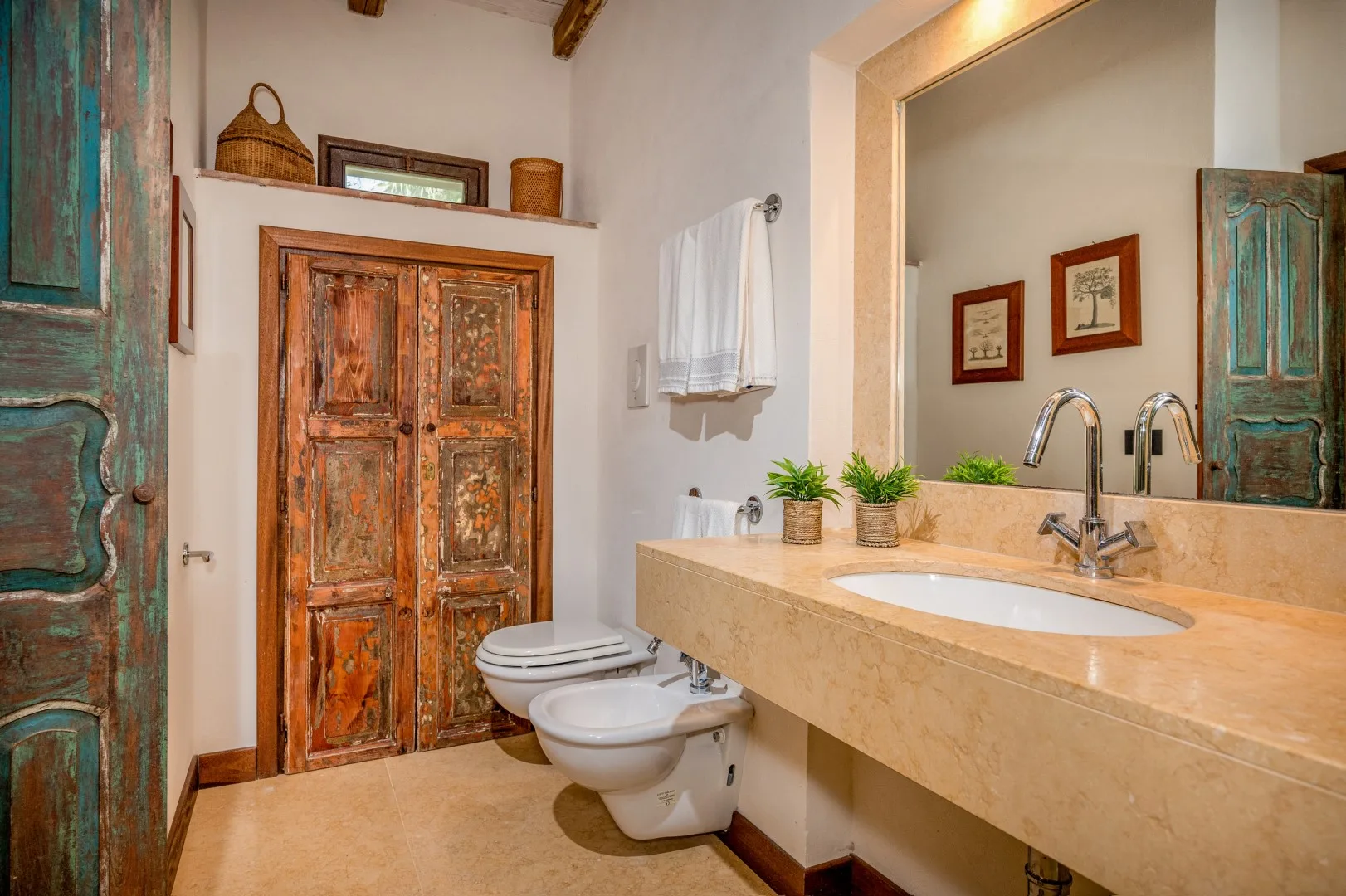 Un baño con un tocador largo, un lavabo sobre encimera y una puerta rústica de madera.