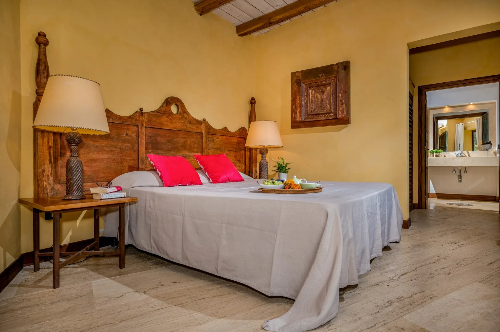 Un dormitorio con una cama grande, almohadas rosas y un cabecero de madera.