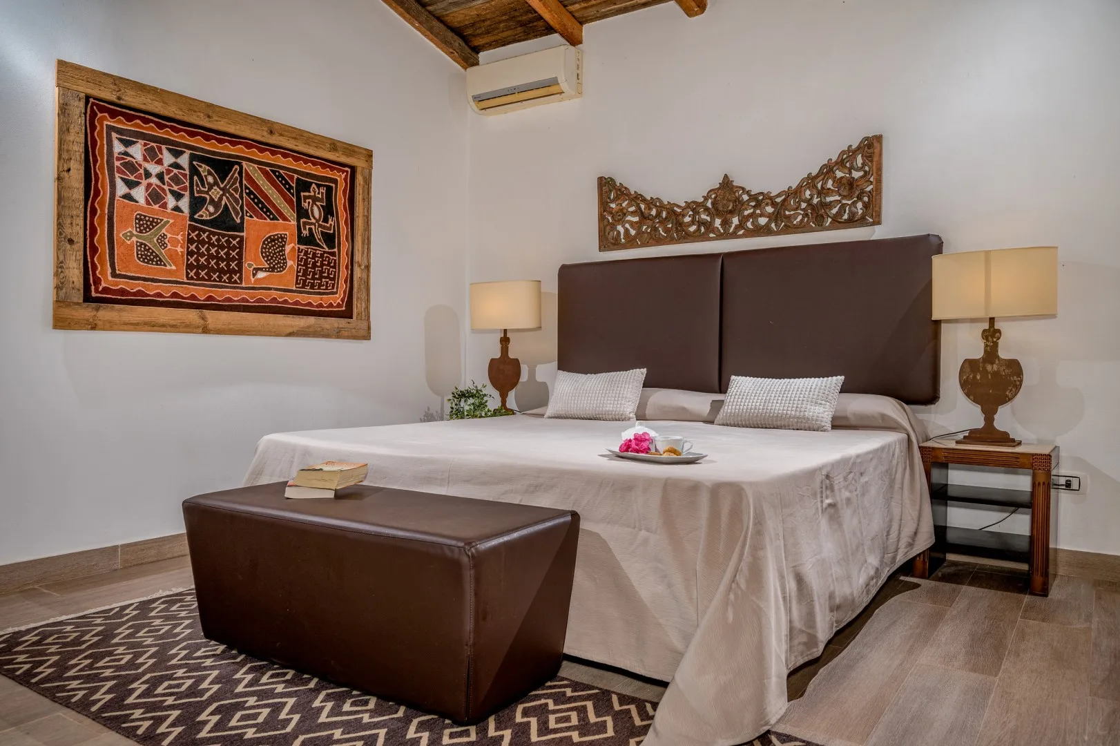 Un dormitorio con una cama grande, lámparas de noche y una alfombra estampada.