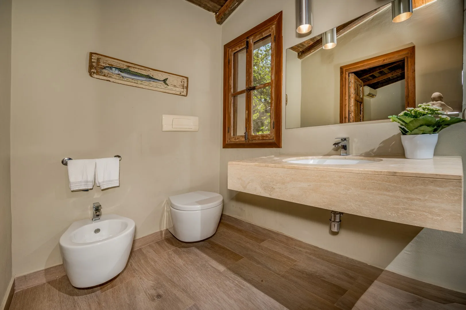 Un baño con un lavabo largo, un lavamanos y un inodoro.
