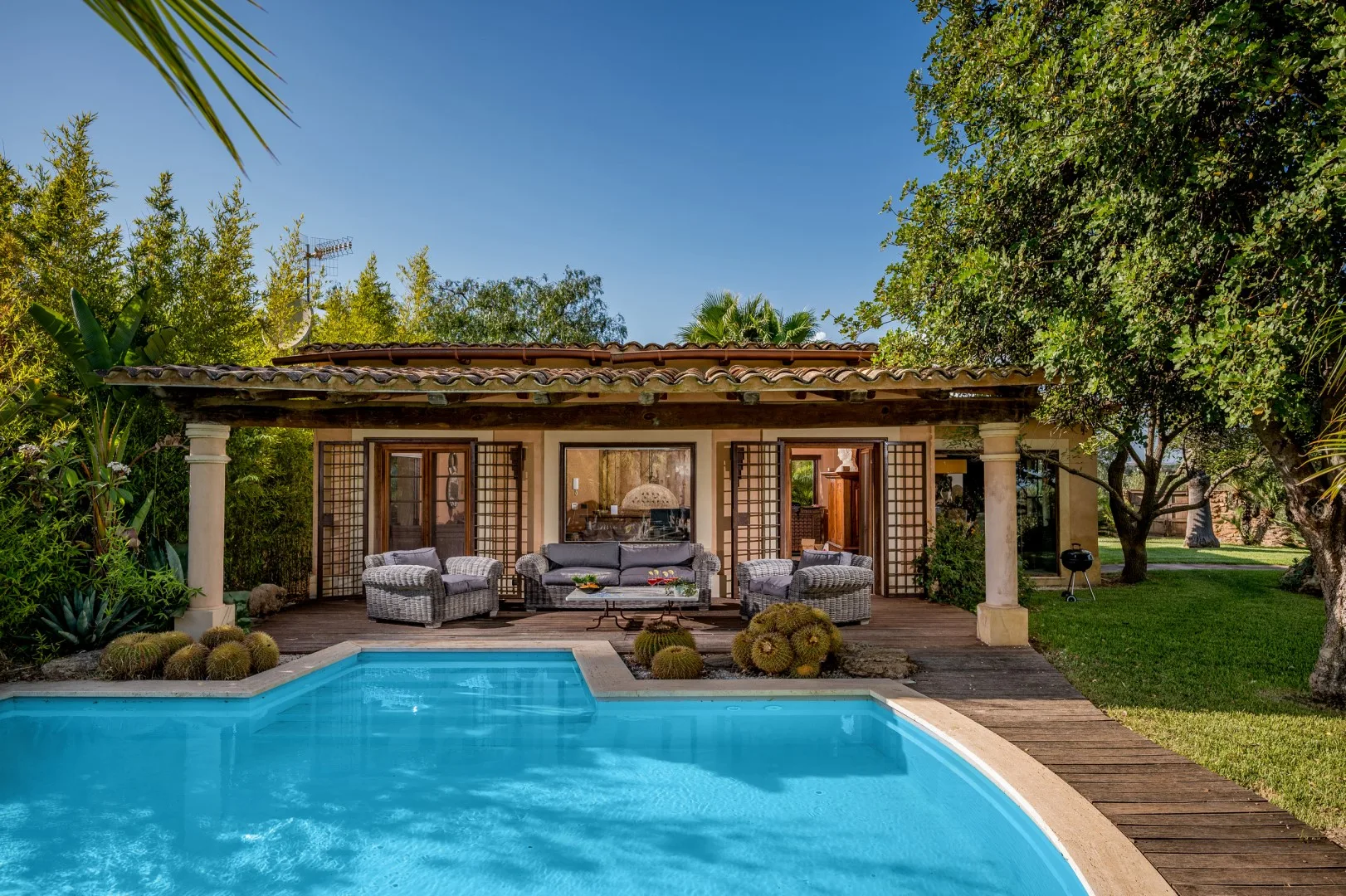 Una piscina y asientos en el patio están frente a una casa de una planta.