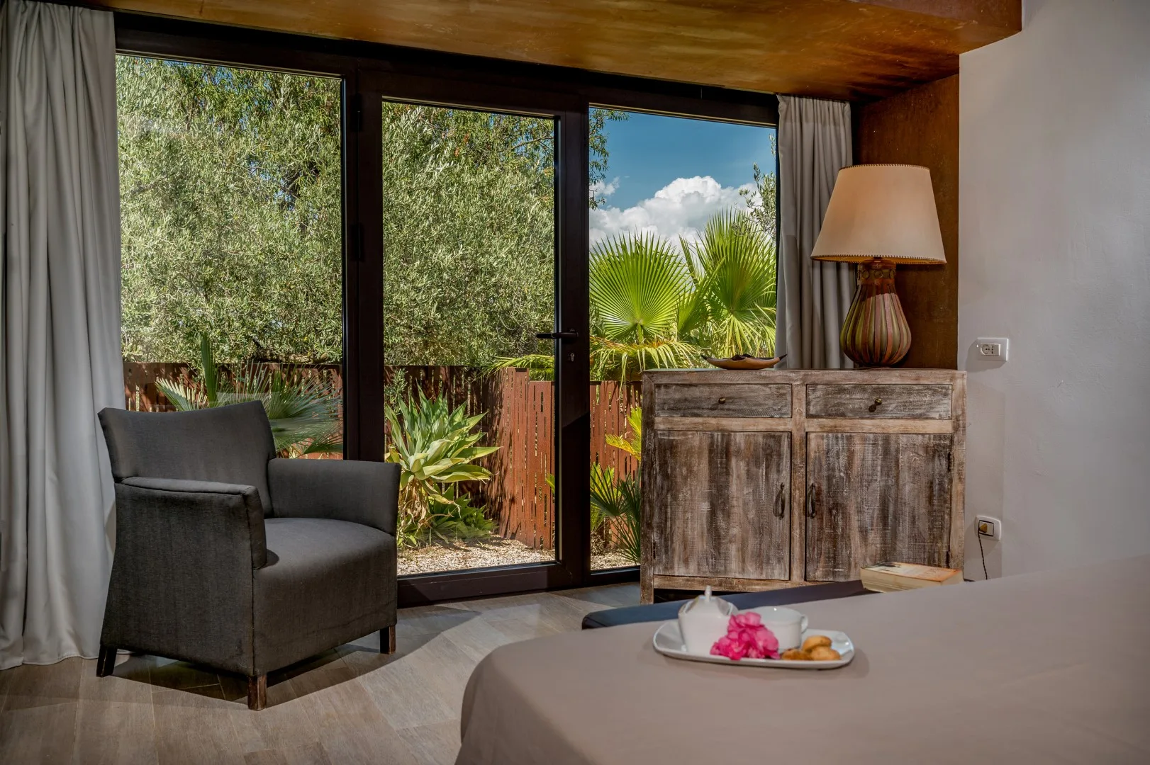 Una zona de estar del dormitorio da a puertas de vidrio con vistas a un jardín frondoso.