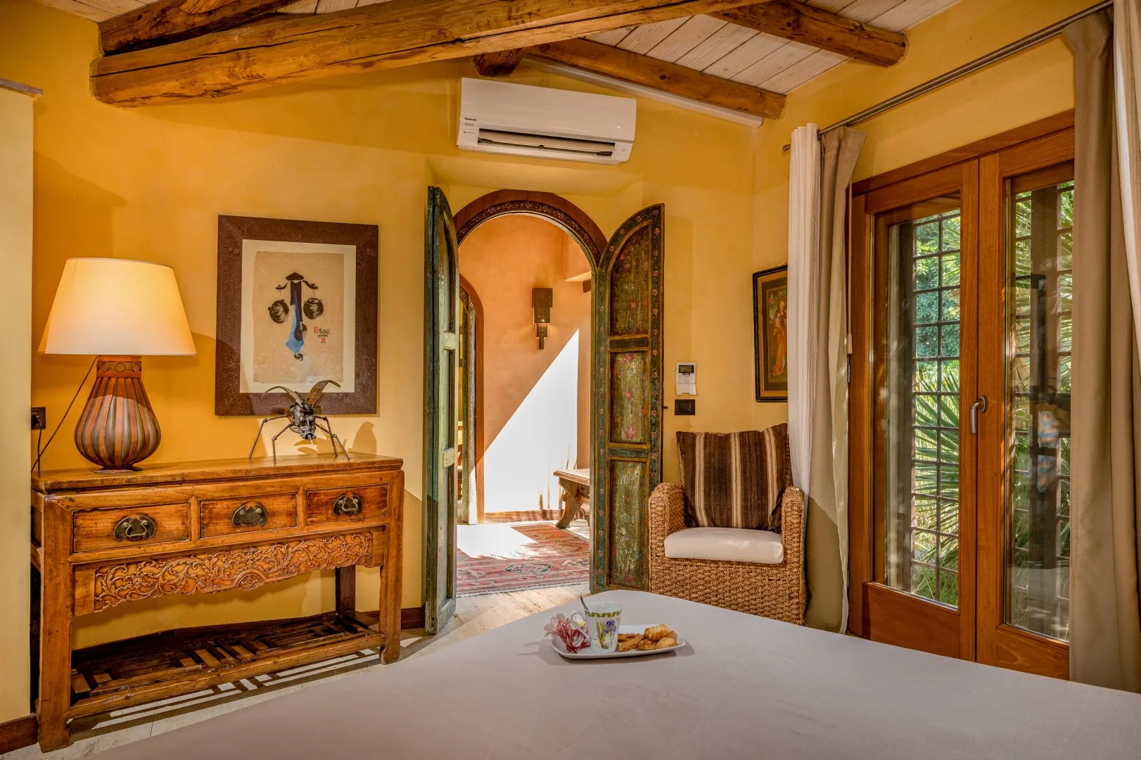 Un dormitorio de tonos cálidos con una cómoda de madera y una puerta arqueada.
