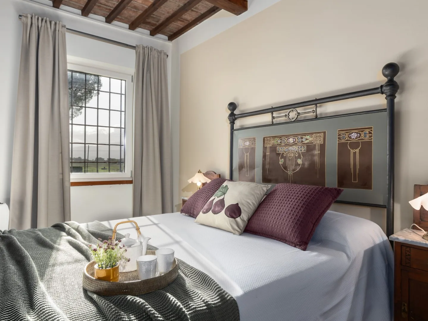 Un dormitorio con una cama bien tendida y una gran ventana con cortinas.