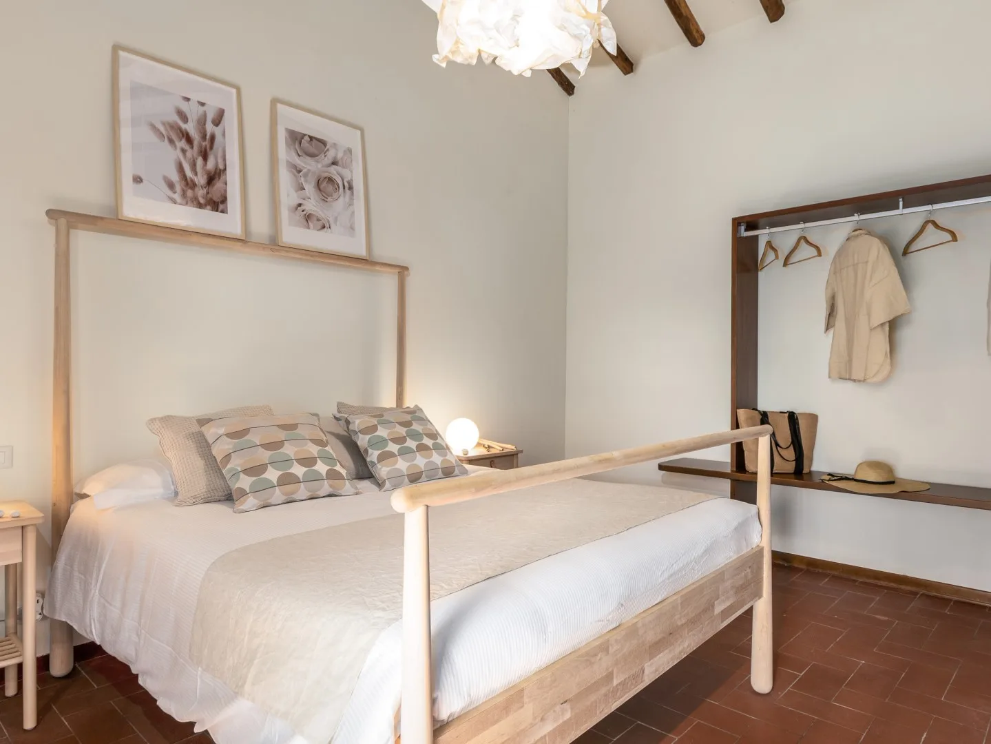 Un dormitorio con una cama bien hecha y cuadros enmarcados sobre el cabecero.