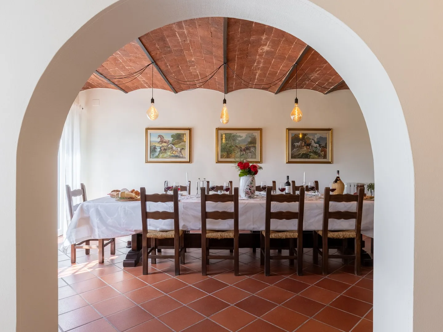 Un comedor con una mesa larga bajo un techo abovedado de ladrillo.