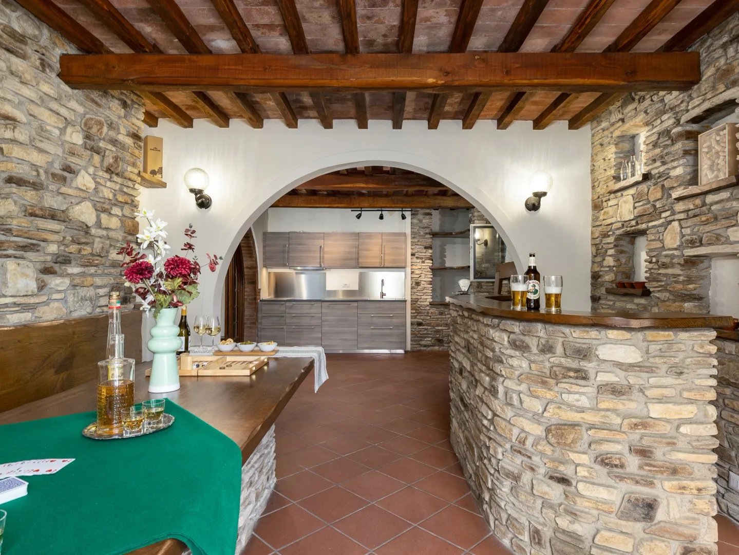 Una habitación con paredes de piedra, una barra curva y una cocina al fondo del arco.