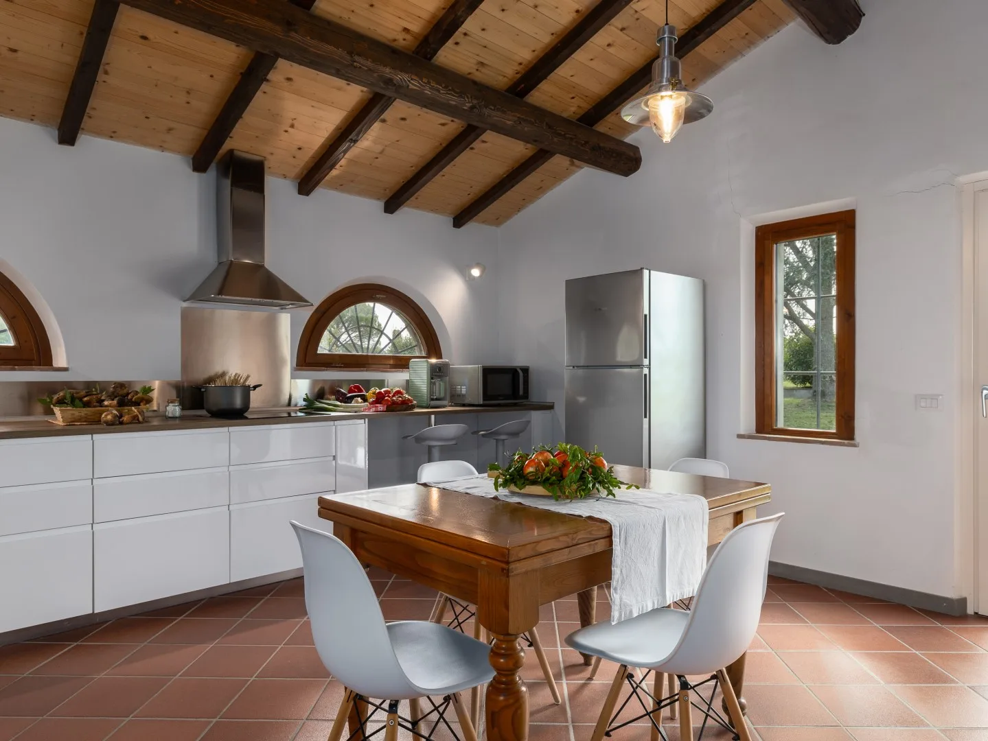 Una cocina y comedor con una mesa de madera y vigas de techo a la vista.