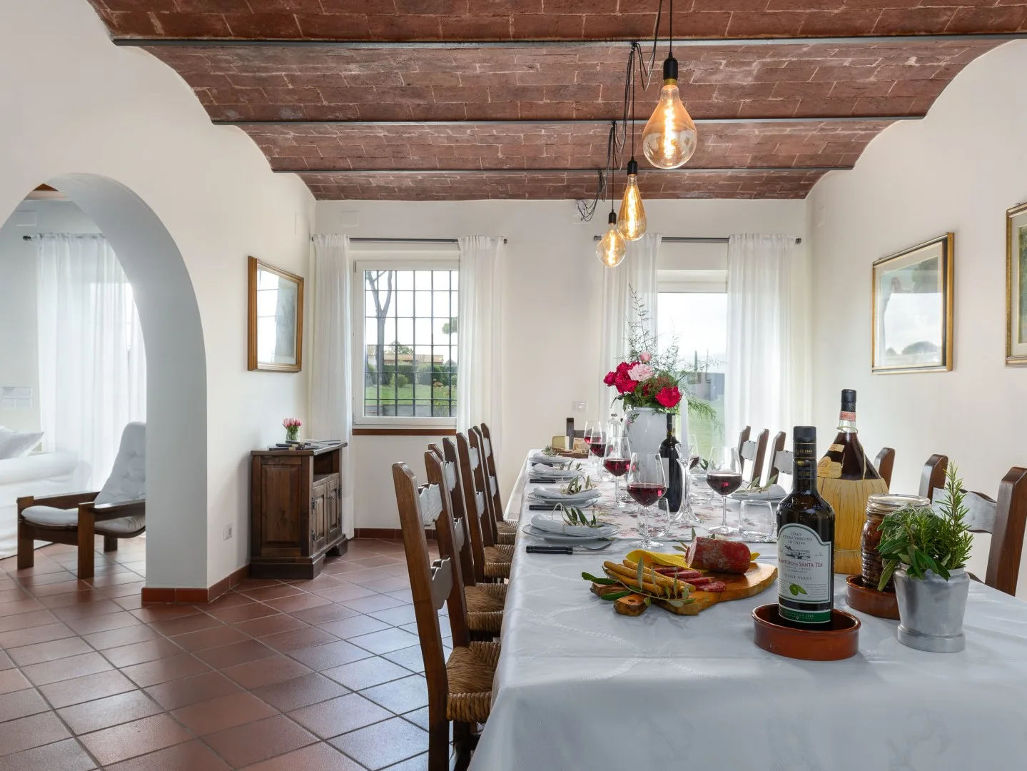 Un comedor con una mesa larga preparada para comer bajo vigas de madera a la vista.