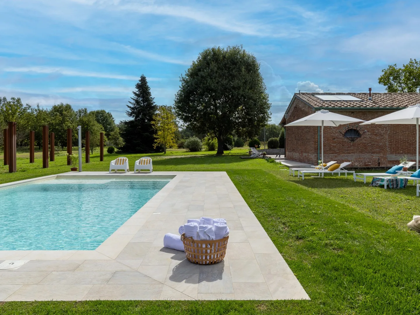Una piscina al aire libre junto a un jardín con césped y un edificio de ladrillo.