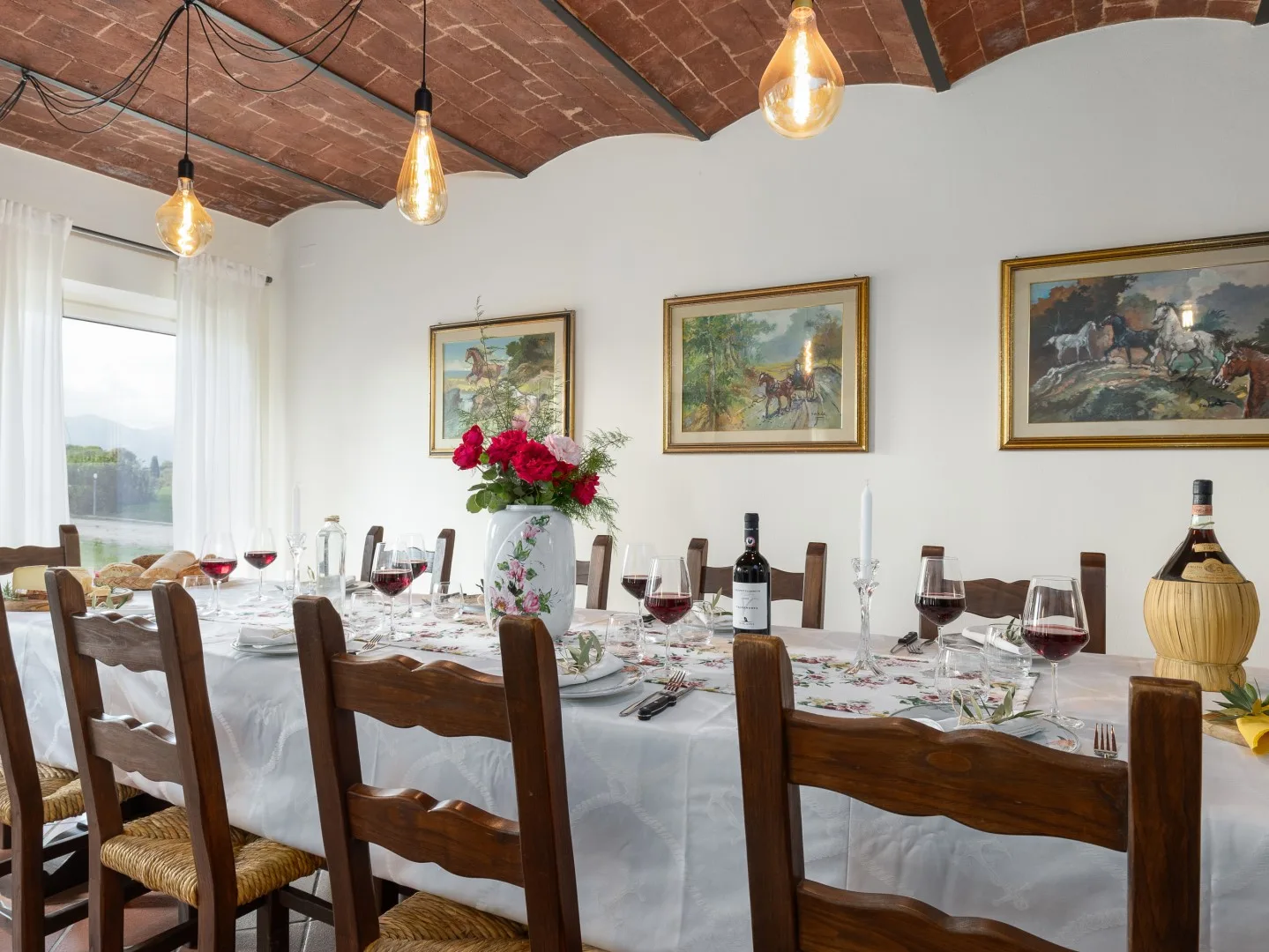 Un comedor con una mesa larga preparada bajo un techo de ladrillo.