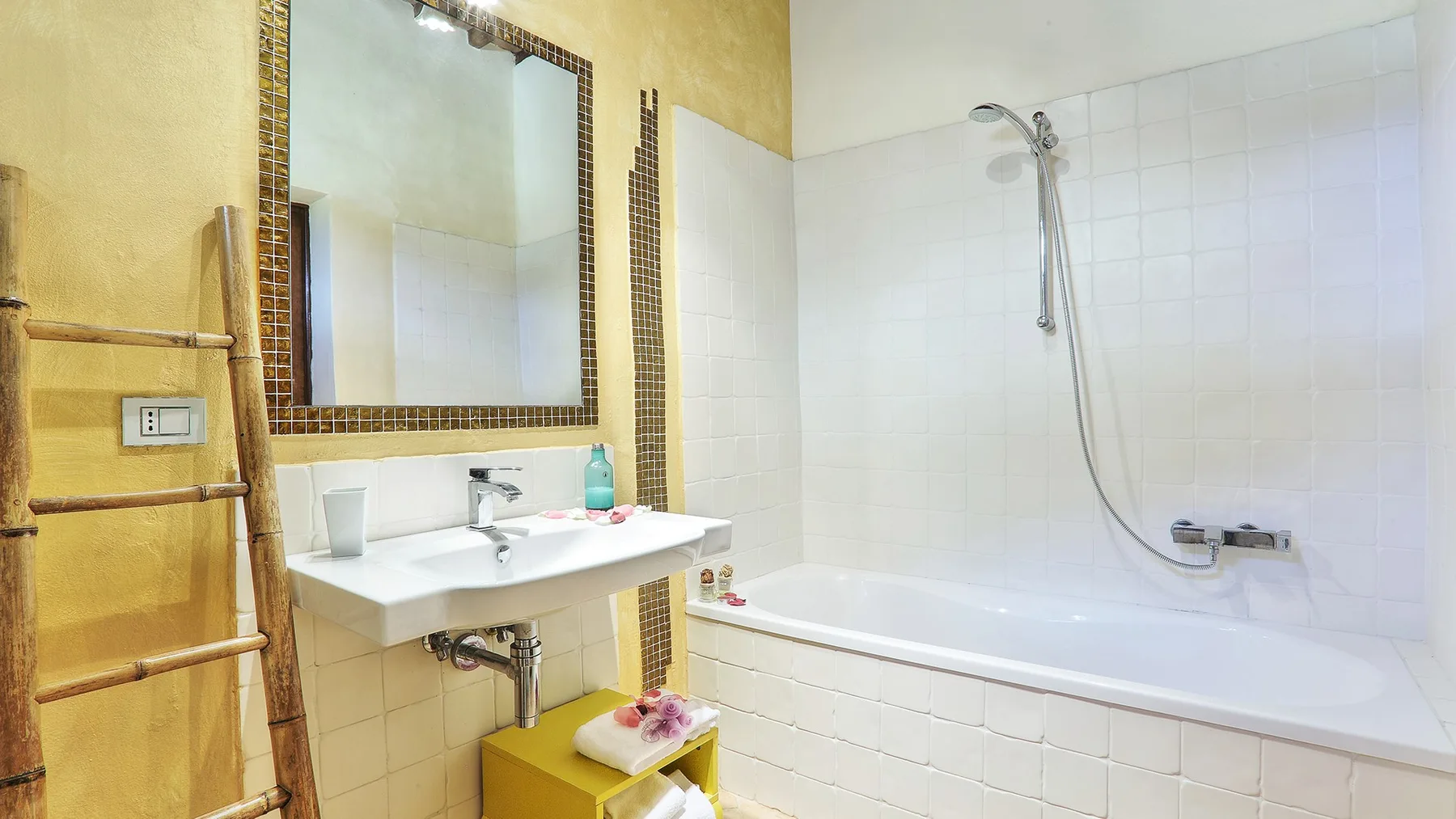 A bathroom with a sink, mirror, and bathtub with a shower.