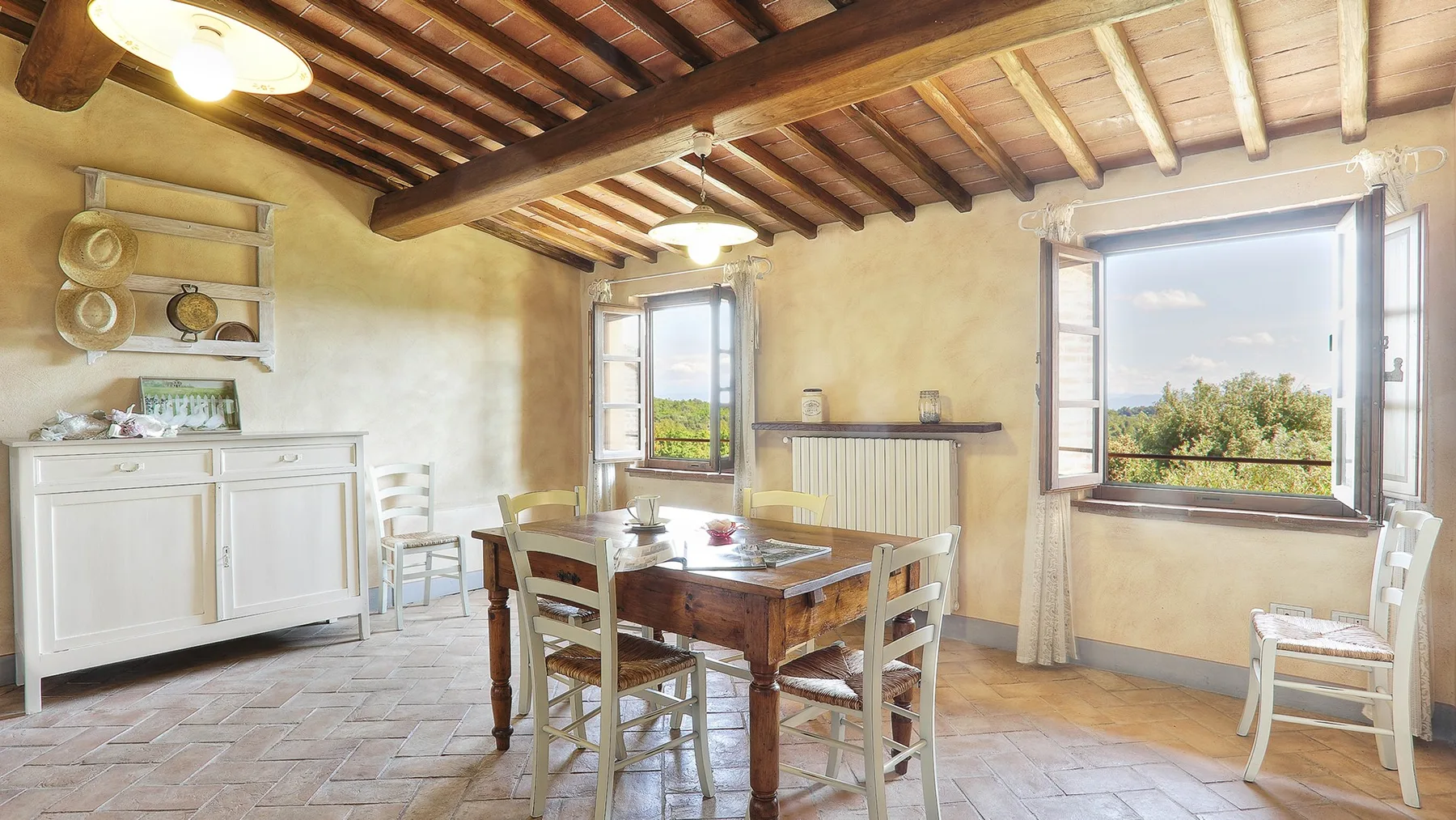A rustic dining room with a wooden table beneath exposed ceiling beams.