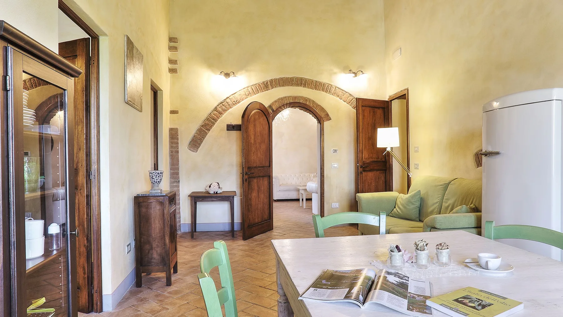A dining area with a table and green seating beside an arched doorway.