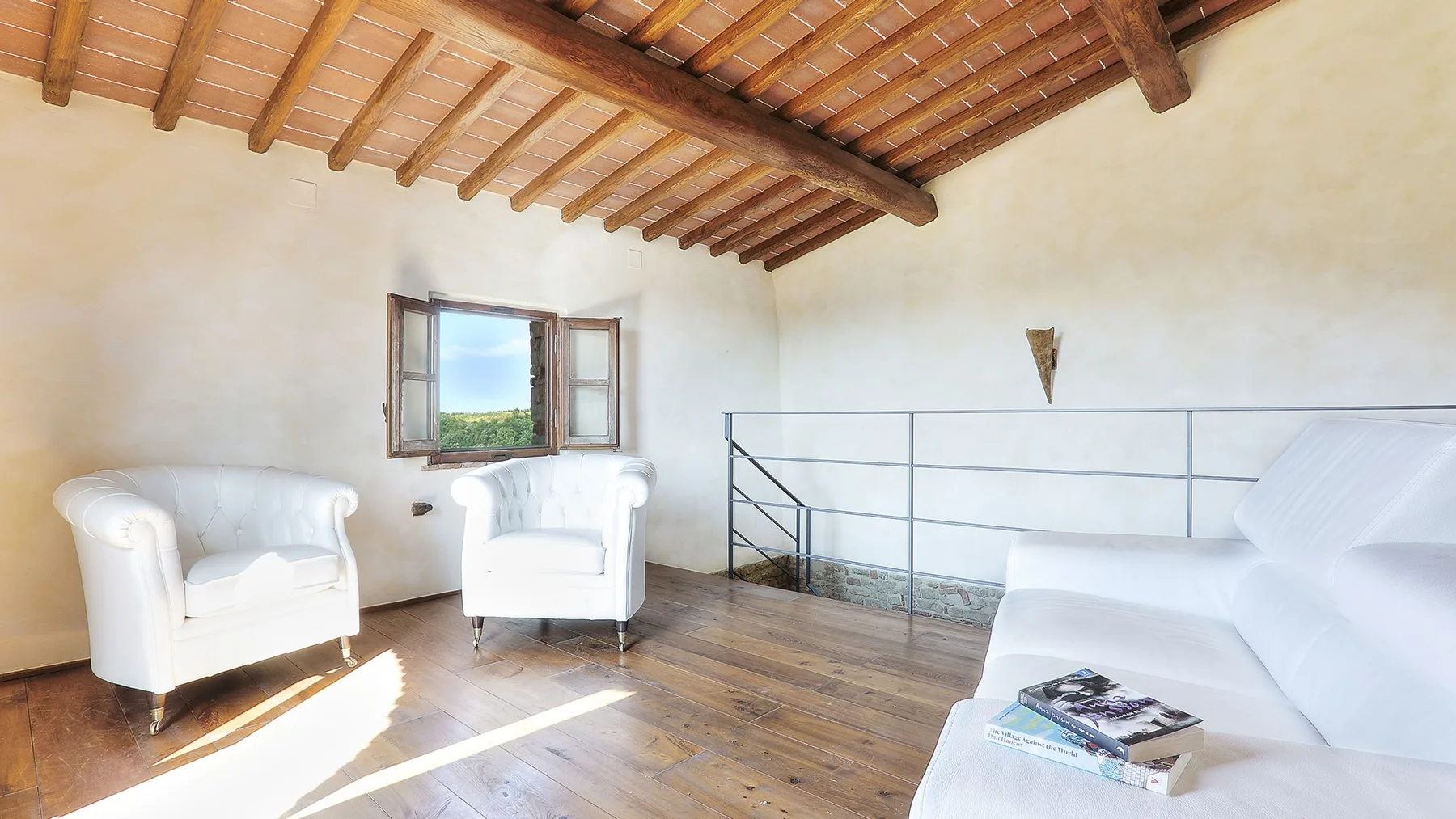 A bright living room with seating, a window, and exposed wooden ceiling beams.